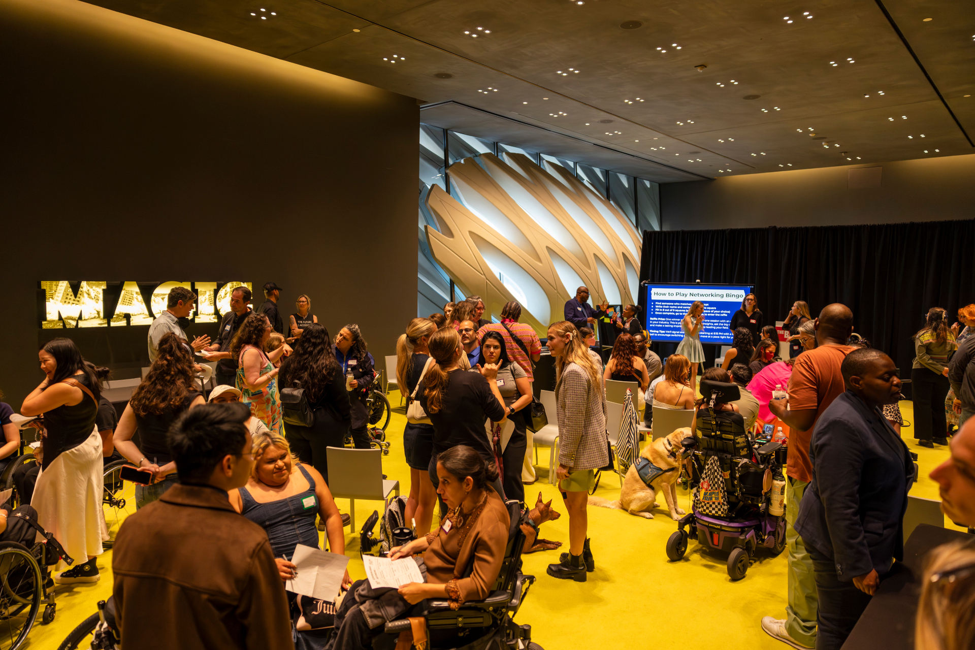 A packed Making Space summit room with attendees networking in front of an illuminated MAGIC installation